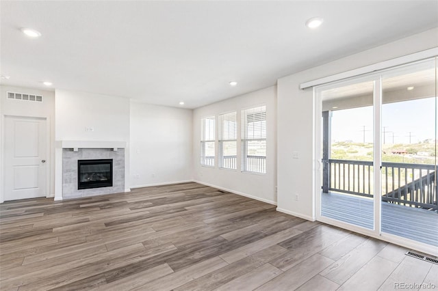 unfurnished living room with a wealth of natural light, visible vents, and wood finished floors