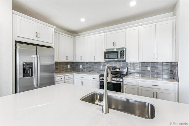 kitchen with recessed lighting, light countertops, white cabinets, appliances with stainless steel finishes, and tasteful backsplash