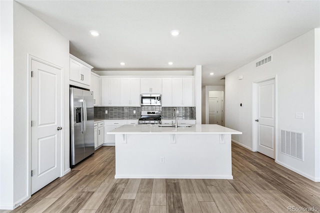 kitchen featuring a sink, tasteful backsplash, visible vents, and stainless steel appliances