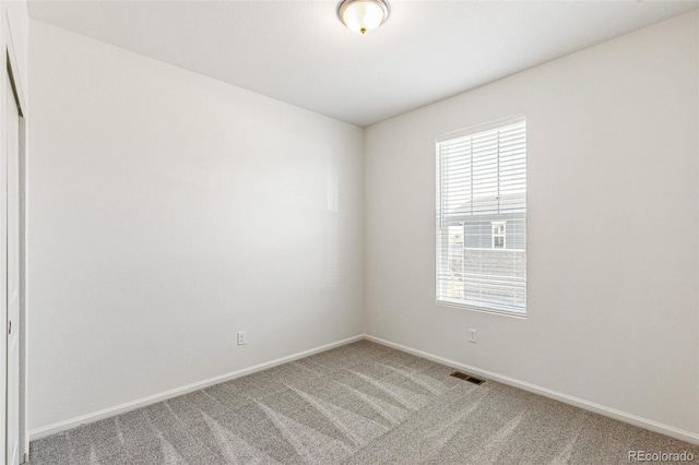 carpeted spare room featuring baseboards and visible vents