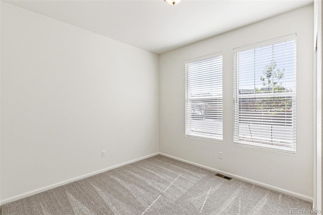 empty room with baseboards, visible vents, and light carpet