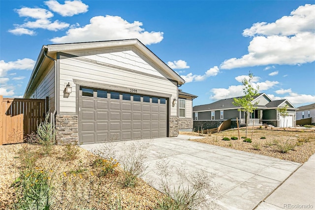 exterior space with stone siding, driveway, and fence