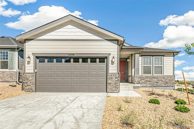 view of front of home with an attached garage, stone siding, and driveway