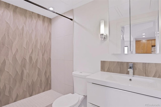 bathroom featuring toilet, vanity, and tiled shower