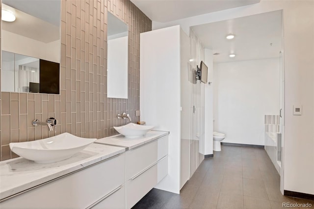 bathroom with toilet, vanity, tile walls, and tasteful backsplash