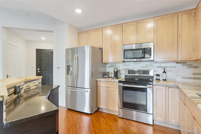 kitchen with stainless steel appliances, light brown cabinets, tasteful backsplash, and light hardwood / wood-style flooring