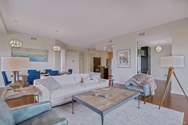 living area with wood finished floors, visible vents, and baseboards