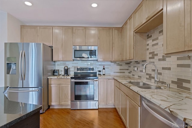 kitchen with light wood finished floors, light brown cabinets, appliances with stainless steel finishes, and a sink