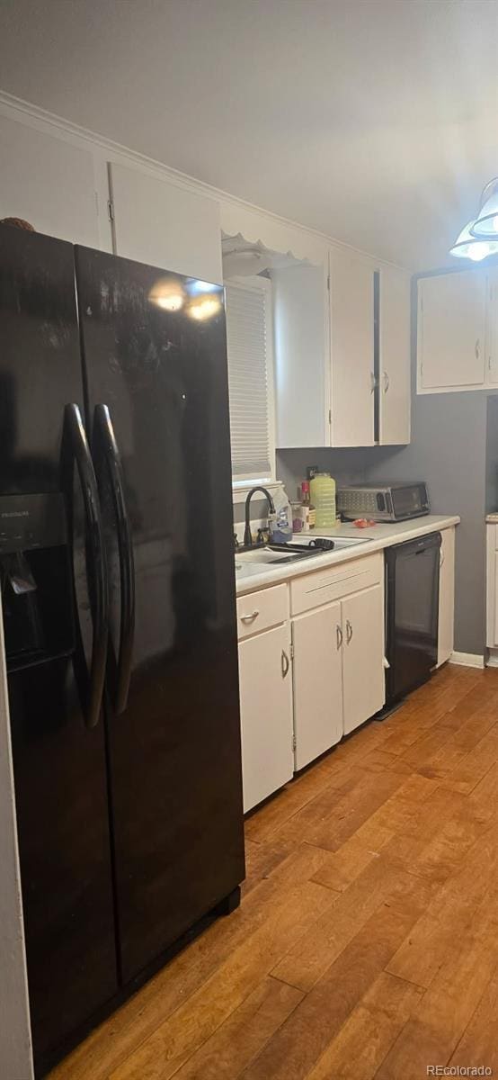 kitchen featuring black fridge, sink, white cabinets, and light hardwood / wood-style floors