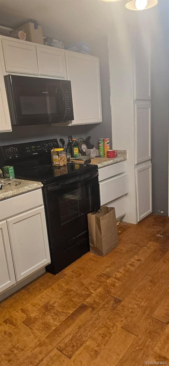 kitchen featuring white cabinets, wood-type flooring, and black appliances