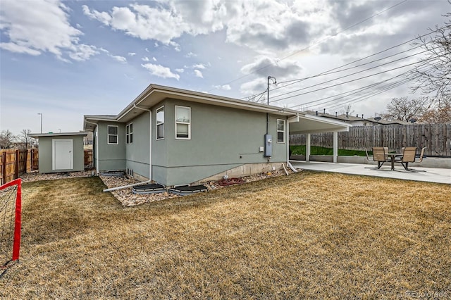 view of side of property with a lawn, a patio, a fenced backyard, and an outbuilding