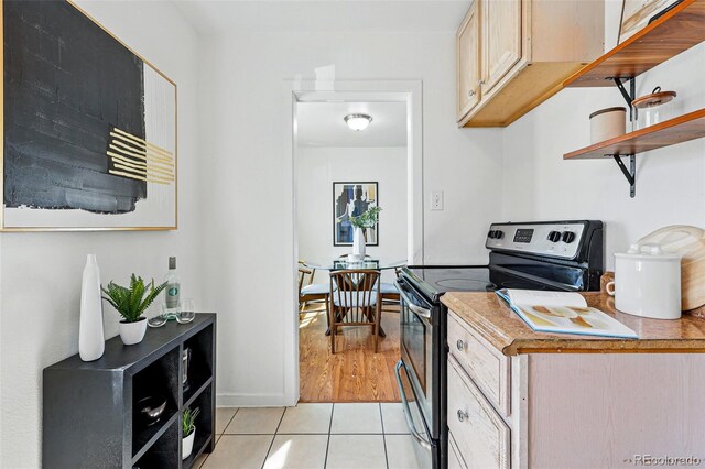 4740 Milwaukee St, Denver, CO 80216 - kitchen featuring stainless steel range with electric stovetop, light tile patterned floors, open shelves, and baseboards