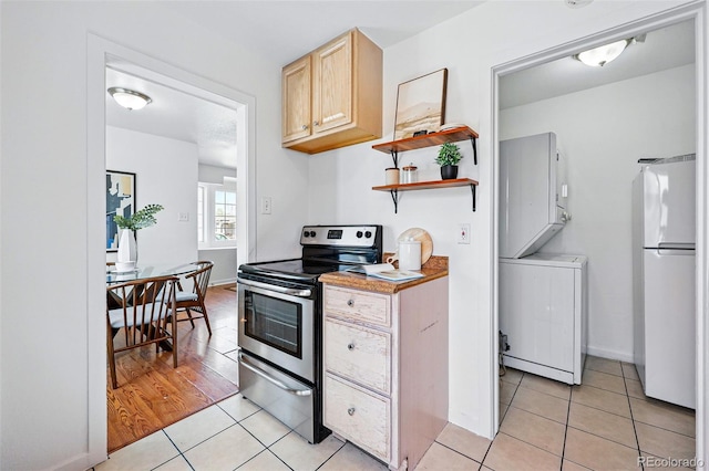 4740 Milwaukee St, Denver, CO 80216 - kitchen with freestanding refrigerator, electric range, light tile patterned floors, estacked washer and dryer, and light brown cabinetry