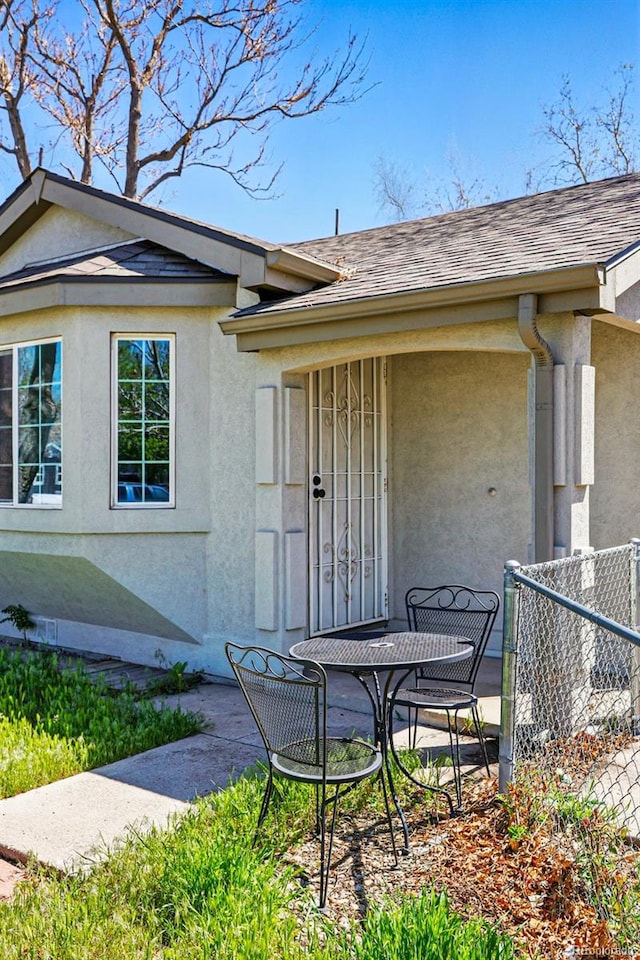 4740 Milwaukee St, Denver, CO 80216 - doorway to property featuring stucco siding, roof with shingles, and fence