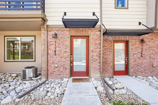 property entrance featuring brick siding and central air condition unit