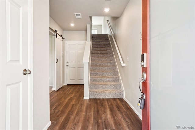 staircase featuring a barn door, baseboards, and wood finished floors