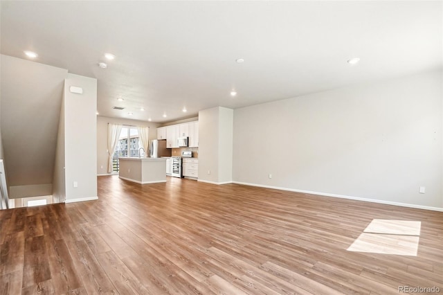 unfurnished living room with light wood finished floors, baseboards, and recessed lighting