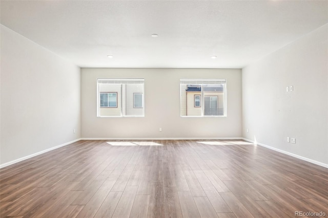unfurnished room with healthy amount of natural light, dark wood-style flooring, and baseboards