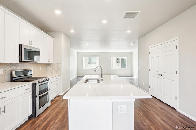 kitchen with appliances with stainless steel finishes, a sink, decorative backsplash, dark wood finished floors, and recessed lighting