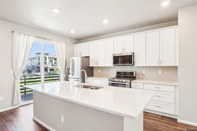 kitchen with appliances with stainless steel finishes, a sink, tasteful backsplash, dark wood finished floors, and recessed lighting