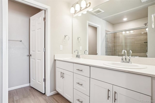 bathroom with a stall shower, double vanity, and baseboards