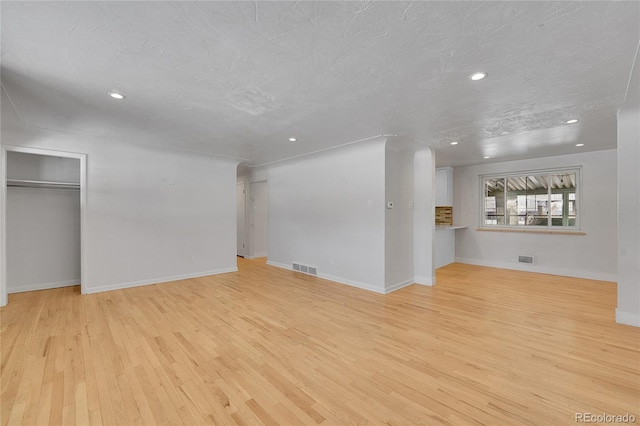 unfurnished living room featuring a textured ceiling and light hardwood / wood-style floors