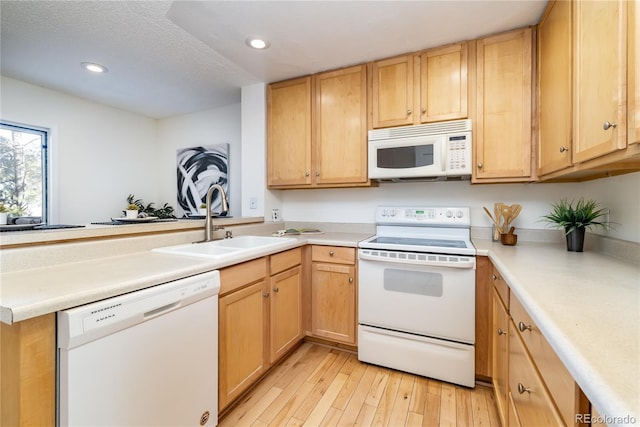 kitchen featuring light brown cabinetry, sink, light wood-type flooring, kitchen peninsula, and white appliances