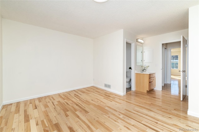 empty room with sink, a textured ceiling, and light hardwood / wood-style flooring