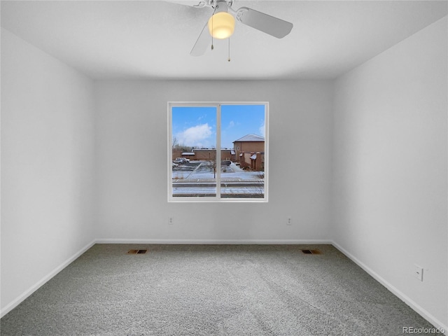 carpeted spare room featuring ceiling fan, visible vents, and baseboards