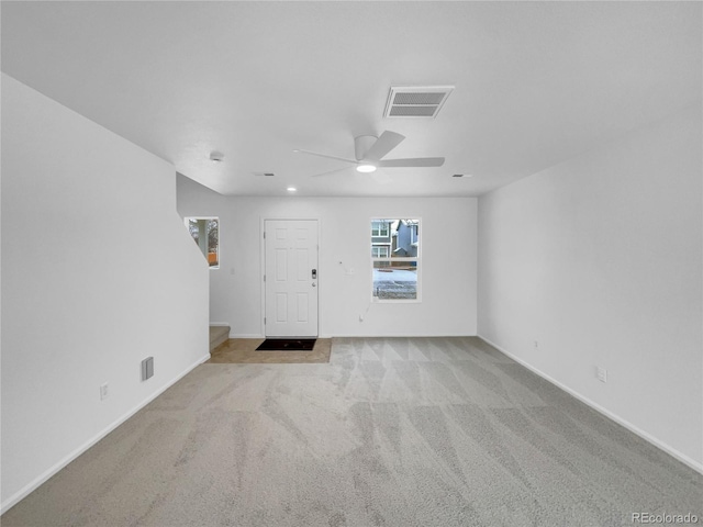 foyer entrance with baseboards, visible vents, a ceiling fan, and light colored carpet