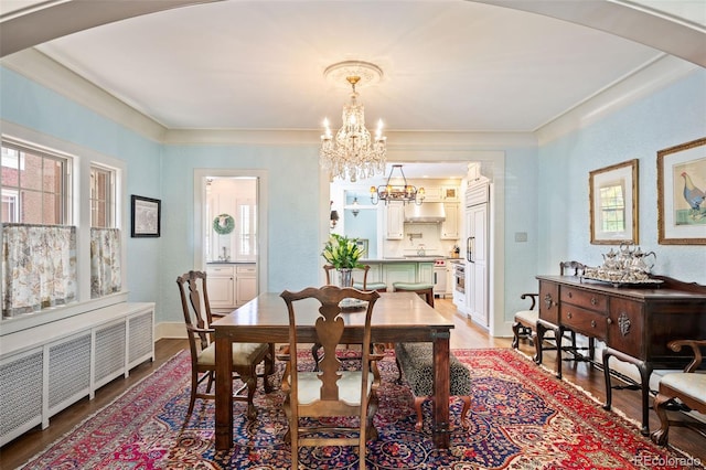 615 N Williams St, Denver, CO 80218 - dining area featuring radiator heating unit, a chandelier, light wood-style flooring, arched walkways, and crown molding