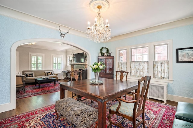 615 N Williams St, Denver, CO 80218 - dining room featuring arched walkways, radiator, a textured wall, crown molding, and wood finished floors