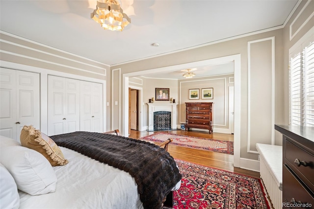 615 N Williams St, Denver, CO 80218 - bedroom featuring a chandelier, wood finished floors, crown molding, a fireplace with flush hearth, and multiple closets