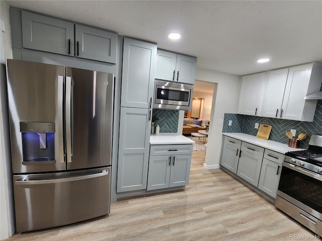 kitchen featuring appliances with stainless steel finishes, light hardwood / wood-style flooring, backsplash, and gray cabinets