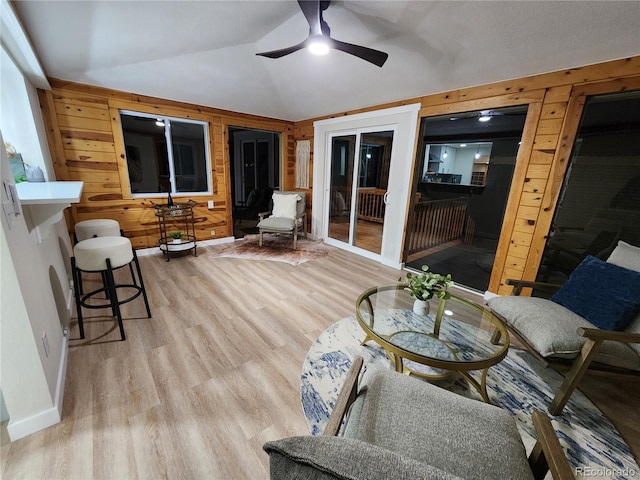 living room featuring lofted ceiling, wood walls, ceiling fan, and light hardwood / wood-style flooring