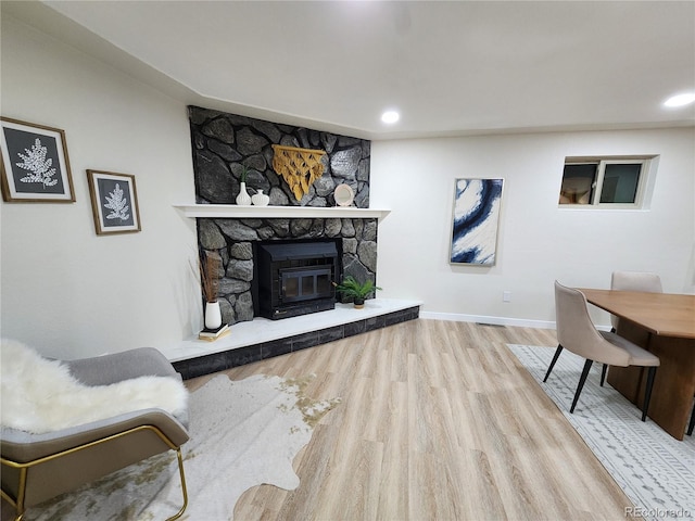 living room with light wood-type flooring and a stone fireplace