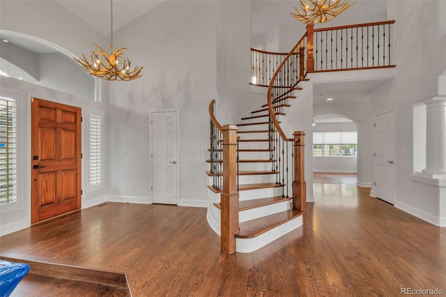 foyer entrance with a notable chandelier, dark hardwood / wood-style floors, and a high ceiling