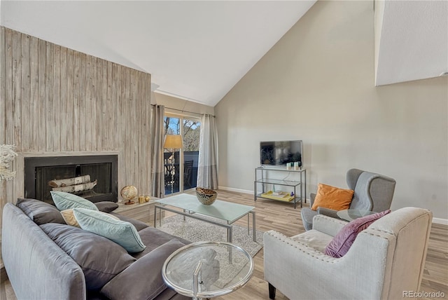 living area with high vaulted ceiling, wood finished floors, baseboards, and a large fireplace