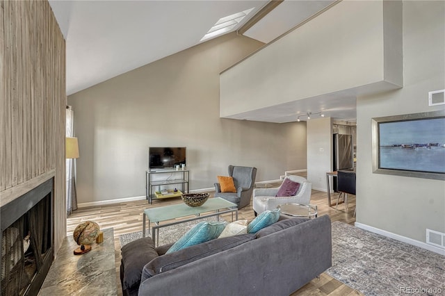 living area with visible vents, high vaulted ceiling, a large fireplace, and baseboards