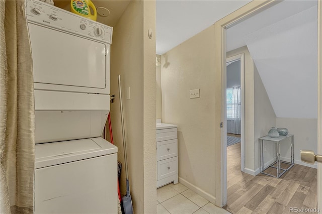 clothes washing area with laundry area, light wood-style floors, baseboards, and stacked washing maching and dryer