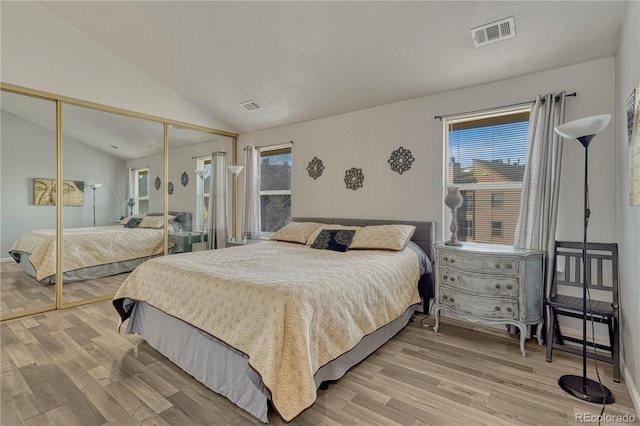 bedroom with visible vents, light wood-type flooring, and lofted ceiling