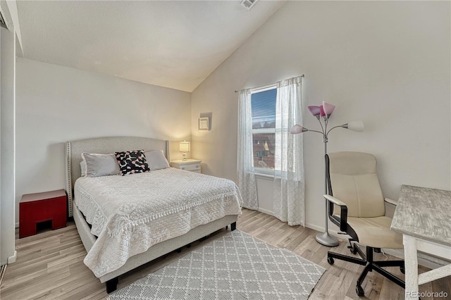 bedroom with vaulted ceiling, wood finished floors, and baseboards