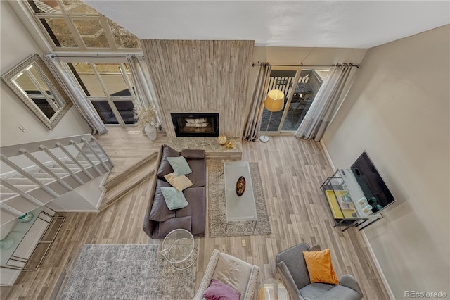 living room with wood finished floors, a fireplace with raised hearth, and baseboards