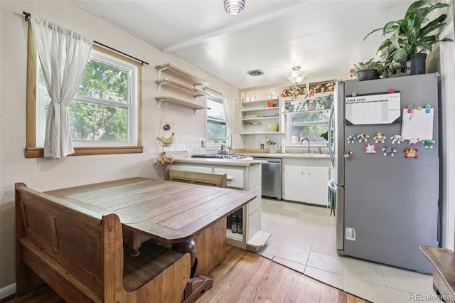 1975 Cody St, Lakewood, CO 80215 - kitchen featuring appliances with stainless steel finishes, open shelves, white cabinets, light countertops, and a peninsula