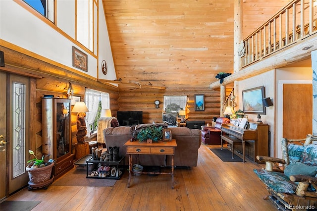 living room with log walls, hardwood / wood-style flooring, and high vaulted ceiling