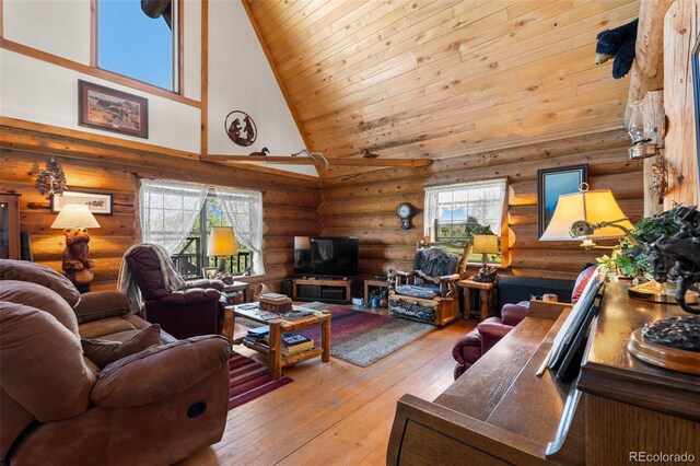 living room featuring rustic walls, wood-type flooring, a wealth of natural light, and high vaulted ceiling