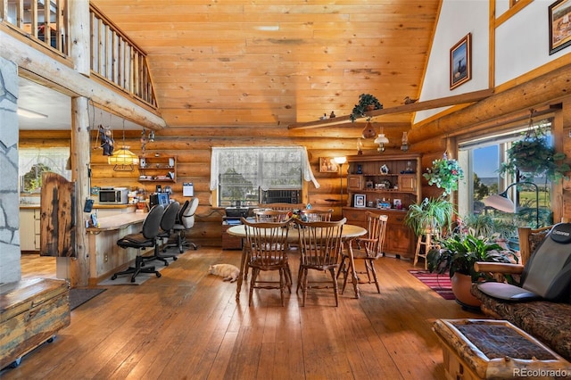 dining room featuring built in study area, log walls, wood-type flooring, and high vaulted ceiling