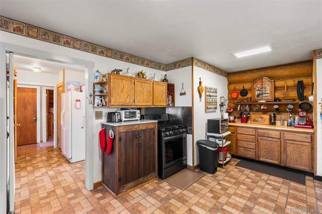 kitchen with gas stove, white refrigerator, and light tile patterned floors