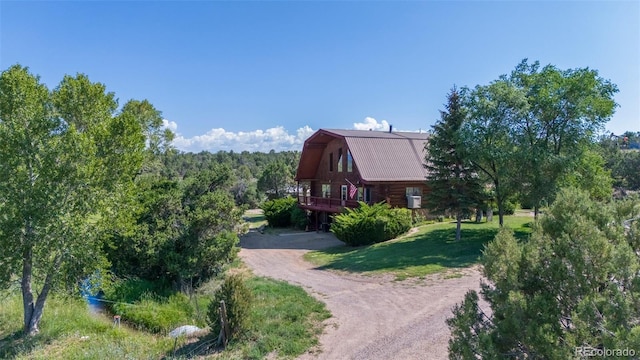 view of side of property with a gambrel roof, a lawn, a barn, dirt driveway, and log exterior