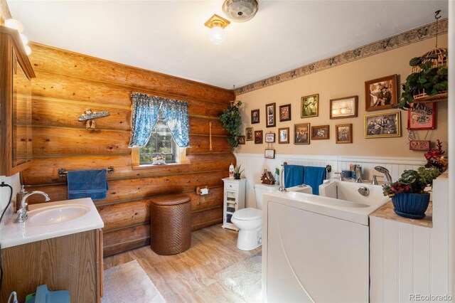 bathroom with vanity, hardwood / wood-style floors, toilet, and log walls